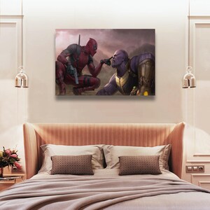 May include: A canvas print featuring a scene with Deadpool and Thanos. Deadpool, in a red and black suit, kneels and points a finger at Thanos's nose. Thanos, in purple and gold armor, is also kneeling. The background is a cloudy, mountainous landscape.
