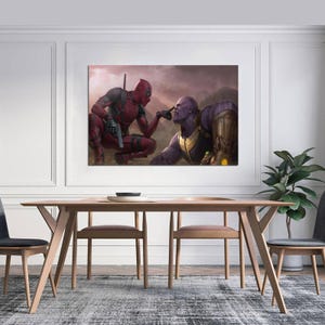 May include: A framed canvas print featuring a dynamic scene of Deadpool and Thanos. Deadpool, in his signature red and black suit, points a finger at Thanos, who is in a purple and gold armored suit. The background is a hazy, mountainous landscape.