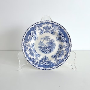 May include: A blue and white porcelain plate with a floral design and a pagoda in the center. The plate is on a clear acrylic stand.