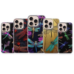 May include: A collection of five phone cases with dragonfly designs. The cases feature various color schemes, including black, gold, teal, and purple, with detailed illustrations of dragonflies and floral accents. The cases are designed to fit a modern smartphone.