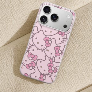 Puede incluir: Funda transparente para tel&eacute;fono con un patr&oacute;n rosa de caras de Hello Kitty con lazos. La funda tiene un borde transparente y cubre la parte trasera y los laterales del tel&eacute;fono.