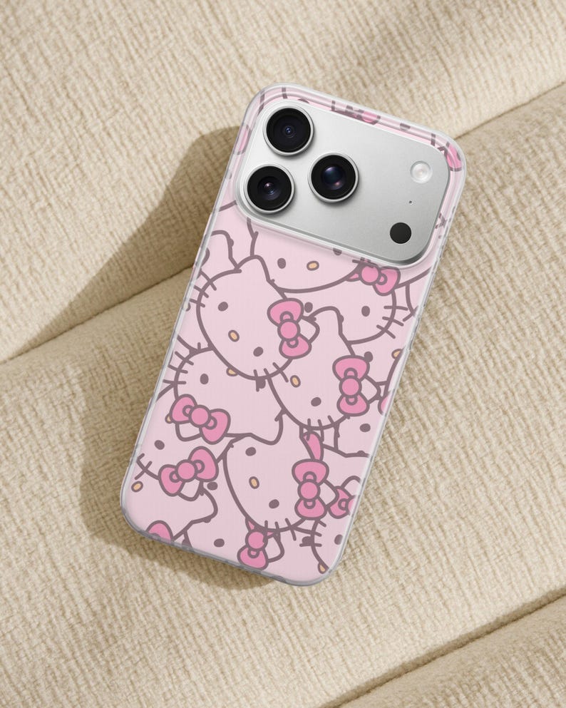 Puede incluir: Funda transparente para tel&eacute;fono con un patr&oacute;n rosa de caras de Hello Kitty con lazos. La funda tiene un borde transparente y cubre la parte trasera y los laterales del tel&eacute;fono.