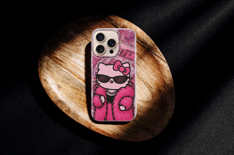 Puede incluir: Funda de tel&eacute;fono transparente con un dise&ntilde;o de Hello Kitty rosa. Hello Kitty lleva gafas de sol, un abrigo de piel rosa y un collar. El fondo tiene un efecto de purpurina rosa y un patr&oacute;n de billetes de d&oacute;lar.