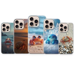 May include: Five phone cases with crab designs. The cases feature various crab illustrations set against beach and winter scenes. The crabs are depicted in different colors, including red, orange, and blue, with detailed artwork.