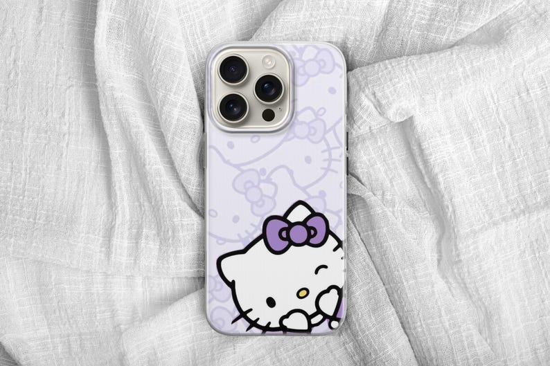 Puede incluir: Una funda de tel&eacute;fono lavanda con un dise&ntilde;o de Hello Kitty blanco y un lazo morado. La funda tiene un patr&oacute;n repetido de caras y lazos de Hello Kitty. La funda del tel&eacute;fono tiene un recorte para la c&aacute;mara y est&aacute; sobre una superficie blanca texturizada.