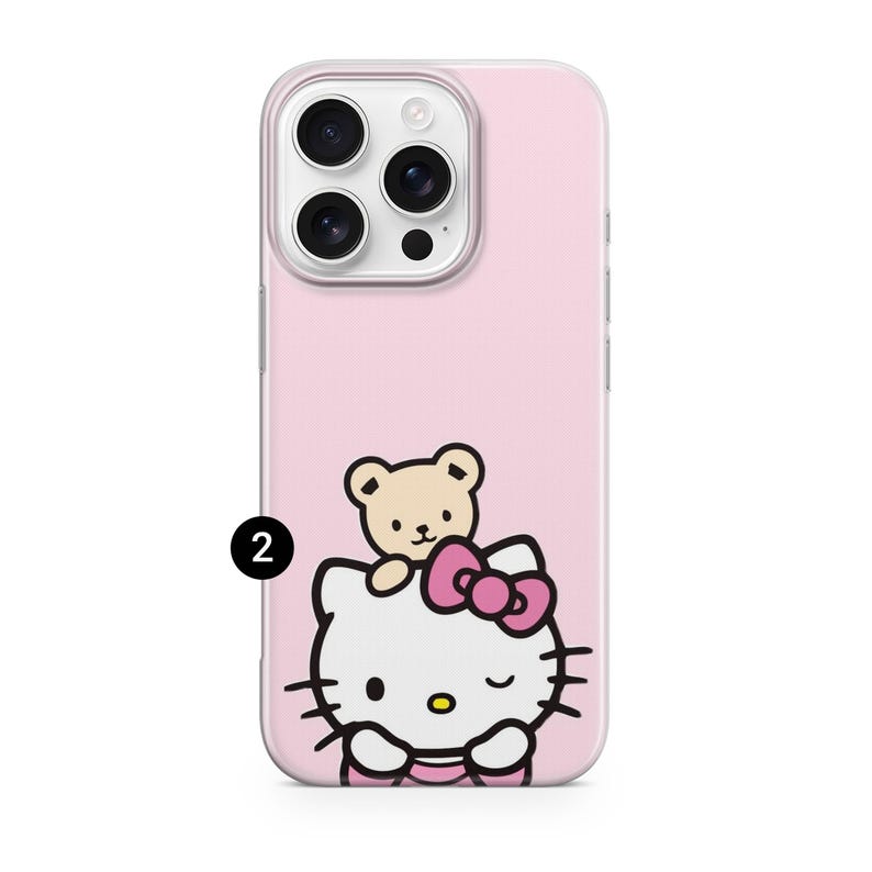 Puede incluir: Funda de tel&eacute;fono rosa con un dise&ntilde;o de Hello Kitty y un oso de peluche. La funda tiene un borde transparente y un fondo rosa. Hello Kitty es blanca con un lazo rosa y gui&ntilde;a un ojo.