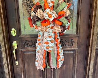 Lazo de diseño otoñal con calabazas y cintas de terciopelo para la decoración de puertas.