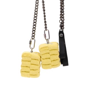May include: Two yellow fire poi with dark metal chains and black fabric handles. The poi are made of a layered, textured material. The chains connect to the poi with metal carabiner clips.