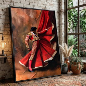 May include: Framed artwork depicting a matador in a red cape and ornate suit. The matador is posed with the cape billowing, set against a textured, earthy background. The artwork is displayed in a room with natural light.