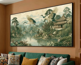 May include: A rectangular wall art print featuring two white cranes with black wing tips flying over a calm lake. The scene includes a traditional East Asian style building with a tiered roof, surrounded by lush green trees, rocky cliffs, and mountains.