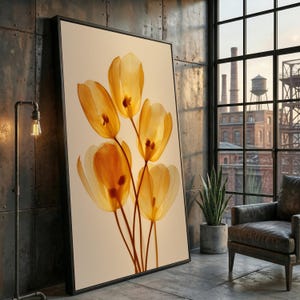 May include: A framed art print featuring a close-up of translucent yellow tulip flowers. The artwork is set against a cream-colored background, with the flowers' details visible. The print is in a black frame, leaning against a textured metal wall.