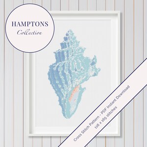 May include: Framed cross-stitch pattern of a seashell in shades of blue and orange. The artwork is part of the "Hamptons Collection." The pattern is 116 x 165 stitches.