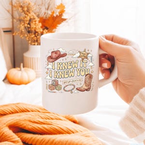 May include: A white ceramic mug featuring a colorful graphic print with the text I KNEW IT I KNEW YOU, a brown cowboy hat, a sheriff star badge, alphabet blocks, a beaded bracelet, and a cowboy boot, along with the phrase you've got a friend in me.