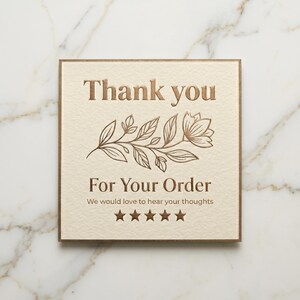 May include: A square off-white card with metallic copper-colored text and a floral line drawing. The text reads Thank you For Your Order We would love to hear your thoughts above five stars. The card has a thin copper-colored border edge.