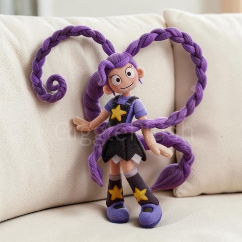Pu&ograve; includere: Bambola in feltro fatta a mano con capelli viola acconciati in lunghe trecce. La bambola indossa una maglietta blu, una gonna nera e stivali con dettagli a stella gialla. Le braccia della bambola sono tese e le trecce formano un cuore.