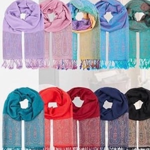 May include: A white ceramic mug with a black handle and the text "But First, Coffee" in a bold, black font. The mug is set against a blurred background, suggesting a cozy setting.