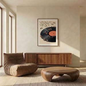Puede incluir: Una impresi&oacute;n art&iacute;stica enmarcada representa un disco de vinilo con peque&ntilde;as figuras reunidas alrededor. La obra de arte cuelga sobre un mueble de madera y una mesa de centro redondeada. A la izquierda hay una silla de sal&oacute;n marr&oacute;n y la habitaci&oacute;n tiene una paleta de colores neutros.