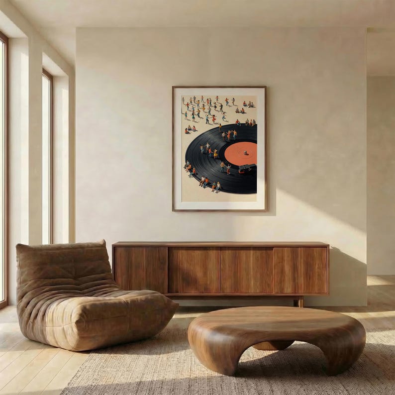 Puede incluir: Una impresi&oacute;n art&iacute;stica enmarcada representa un disco de vinilo con peque&ntilde;as figuras reunidas alrededor. La obra de arte cuelga sobre un mueble de madera y una mesa de centro redondeada. A la izquierda hay una silla de sal&oacute;n marr&oacute;n y la habitaci&oacute;n tiene una paleta de colores neutros.
