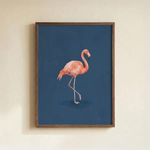 May include: A framed print featuring a watercolor painting of a flamingo. The flamingo is depicted in shades of pink and orange against a deep blue background. The artwork is encased in a brown wooden frame, adding a touch of warmth.