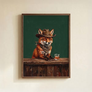 May include: A framed art print featuring a fox dressed as a cowboy, wearing a brown hat and bandana, with a glass of whiskey on a wooden bar. The background is a dark green color.