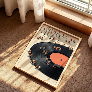 Puede incluir: Una obra de arte enmarcada que presenta un disco de vinilo negro con figuras en miniatura. Algunas figuras bailan, mientras que otras est&aacute;n sentadas alrededor del borde del disco. El disco tiene un centro naranja y est&aacute; sobre un fondo claro.