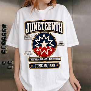 May include: A white short-sleeve t-shirt featuring a graphic with the text JUNETEENTH, STAR OF FREEDOM, NEW HORIZON, SECOND INDEPENDENCE DAY, THE STAR THE ARC THE FREEDOM, and JUNE 19, 1865, centered around a circular emblem with a star.