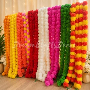 Puede incluir: Una colección de guirnaldas colgantes verticales hechas de flores de caléndula artificiales en colores vibrantes que incluyen naranja, amarillo, rosa, rojo, blanco y verde. Cada hebra consta de numerosos pétalos de tela pequeños y redondos.
