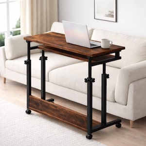 May include: A brown and black adjustable laptop desk with a laptop and a mug on top. The desk has a lower shelf and is on wheels. The desk is next to a white sofa.