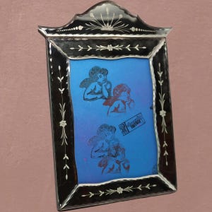 Pu&ograve; includere: Uno specchio da parete rettangolare con cornice in vetro nero caratterizzata da motivi floreali bianchi incisi e una parte superiore ad arco decorativa. Il pannello centrale in vetro blu mostra due cherubini incisi e un'etichetta Beautiful Vintage.