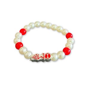Puede incluir: Una pulsera de cuentas con cuentas blancas y rojas alternas. La pulsera tiene un dije plateado con las letras "4WD" en rojo y blanco. Las cuentas son redondas y parecen brillantes.