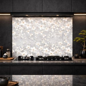 Pode incluir: Uma cozinha moderna com um painel traseiro floral com flores brancas sobre um fundo cinza. A cozinha tem armários pretos, uma placa de fogão preta e itens decorativos, incluindo um bonsai em um vaso preto.