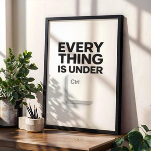 Peut inclure: Une affiche encadrée avec le texte "EVERYTHING IS UNDER Ctrl" en noir, avec un graphique de touche Ctrl blanche. L'affiche est dans un cadre noir, posée sur une surface en bois avec une plante en pot et un porte-crayons.