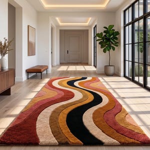 May include: A rectangular area rug featuring a repeating pattern of wavy, curved lines in shades of deep red, burnt orange, mustard yellow, cream, and black. The rug has a textured, plush pile surface and is positioned on a light wood floor.