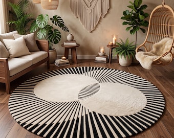 Op de afbeelding: Een groot rond vloerkleed met een opvallend geometrisch patroon in zwart en crème. Het ontwerp bestaat uit twee overlappende crèmekleurige cirkels tegen een achtergrond van uitstralende zwarte en crèmekleurige lijnen naar de rand.