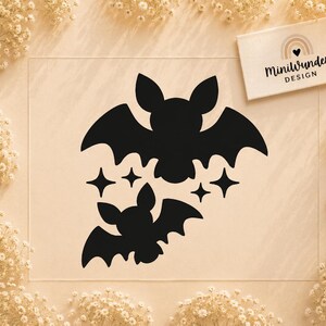 Puede incluir: Un adhesivo de vinilo negro con dos siluetas de murciélagos y cuatro estrellas de cuatro puntas. Una tarjeta blanca rectangular en la esquina superior derecha muestra un icono de arcoíris con un corazón y el texto MiniWunder DESIGN.