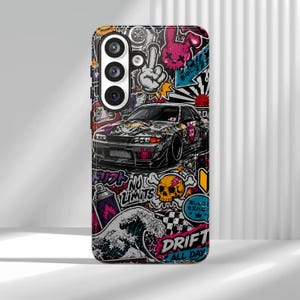 Puede incluir: Una funda para smartphone con un collage vibrante de gráficos de arte callejero, que incluye una ilustración detallada de un coche deportivo, una calavera, una ola y varios caracteres japoneses. El diseño incorpora colores llamativos como rosa, amarillo y negro.