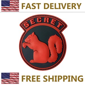 May include: A red squirrel emblem with the word "SECRET" in red lettering. The squirrel is set against a black background within a circular design. The emblem is surrounded by a red border.