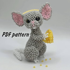 Op de afbeelding: Een kralen muis figuur in grijs, roze en geel, met een gele kaaswig. De muis heeft grote roze oren en een witte staart. De tekst "PDF pattern" staat in het zwart. Het beeldje is gemaakt van kleine kralen.