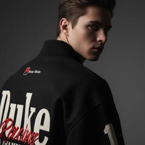 May include: Black varsity jacket with white and red lettering. The jacket features the text "Duke Racing" and the number "1". The words "Motor Works" are also visible on the jacket.