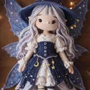 Puede incluir: Muñeca de ganchillo hecha a mano vestida de hada, con un vestido azul marino adornado con estrellas y una luna creciente. La muñeca tiene pelo lavanda, alas azules y un sombrero a juego con una luna creciente. La muñeca mide unos 25 cm.