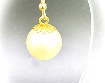 May include: Gold tone earring with a white pearl and a decorative filigree design.