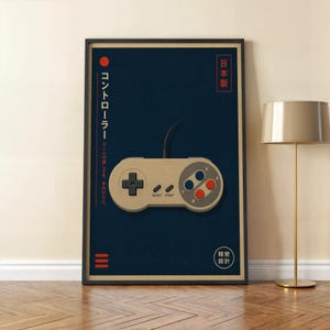 May include: Framed poster with a beige video game controller on a dark blue background. The controller has a plus-shaped directional pad, buttons, and the text "SELECT START". Japanese text and design elements are also present.