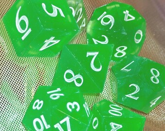May include: A set of six translucent green polyhedral dice with white engraved numbers. The collection includes various shapes such as a d20, d12, d10, d8, d6, and d4, each featuring clear, legible numerals for tabletop gaming and role-playing activities.