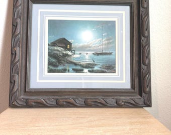 Lámina vintage de Windberg con escena de la costa a la luz de la luna y un velero en el puerto, con marco de madera tallada.