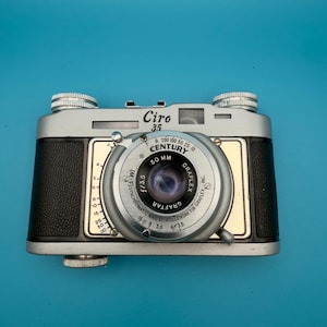 Könnte beinhalten: Ein Set aus drei Keramikbechern mit gesprenkelter, matter Oberfläche. Die Becher sind in Creme-, Hellgrau- und Dunkelgrautönen gehalten. Jeder Becher hat ein schlichtes, minimalistisches Design, perfekt für Kaffee oder Tee.