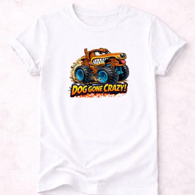 以下が含まれることがあります： 白いTシャツ。犬をモチーフにしたカートゥーンのモンスタートラックのデザイン。トラックは茶色とオレンジ色で、青い車輪があり、「DOG GONE CRAZY!」の文字がカラフルなフォントで表示されています。犬はしかめっ面をしています。
