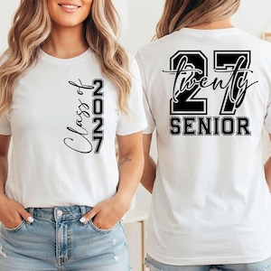May include: White t-shirt with the text "Class of 2027" on the front and "27 Twenty SENIOR" on the back, in black lettering. The shirt is a crew neck style and is being worn by a person.