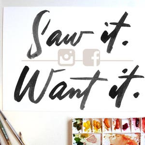 Könnte beinhalten: Ein Aquarellgemälde auf weißem Papier mit den Worten "Saw it. Want it." in schwarzen Pinselstrichen. Die Instagram- und Facebook-Logos sind sichtbar. Pinsel und eine Aquarellpalette mit verschiedenen Farben sind im Bild.