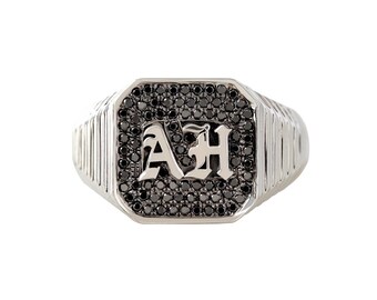 May include: A silver signet ring with a black diamond pave setting featuring the initials "AH" in a gothic font.