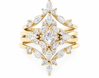 May include: A gold ring set featuring a central princess-cut diamond surrounded by marquise and round-cut diamonds in a symmetrical, pointed arrangement. The design includes three stacked bands with intricate, prong-set diamond accents throughout.